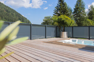 Leeb Geländer Modell Vision mit mattgrauer Glasfüllung - terrassenartiger Balkon modernes Holzhaus, Innenansicht mit verbautem Whirlpool